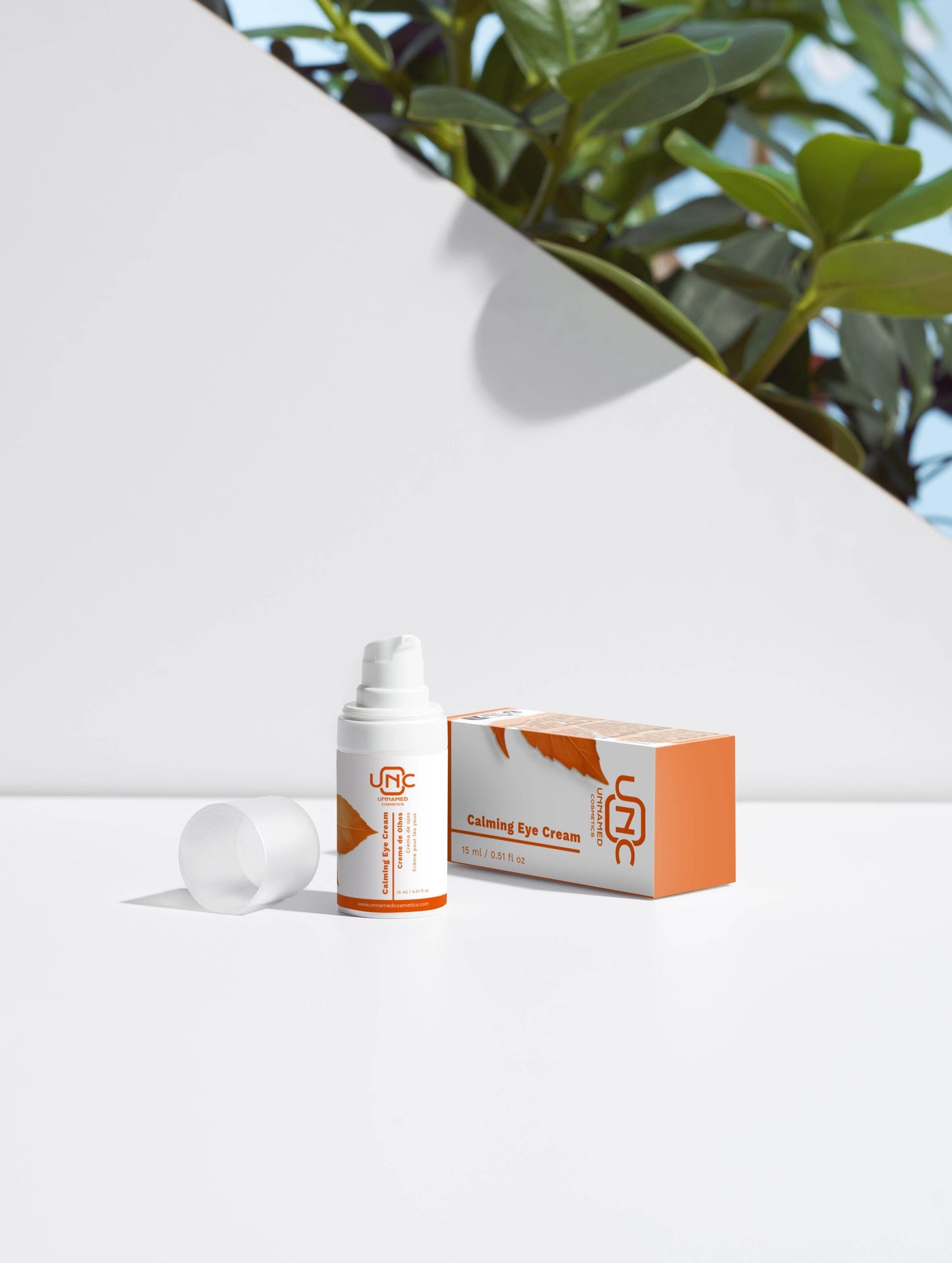 Creme para olhos calmante em embalagem branca e laranja da Unnamed Cosmetics com caixa ao lado