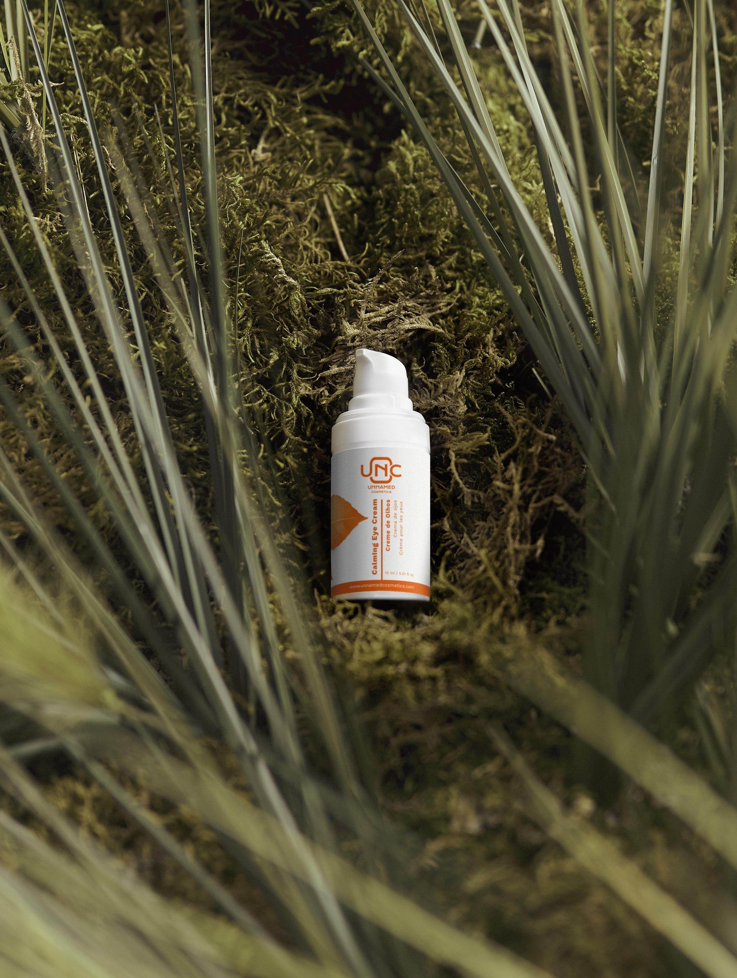 Frasco branco de creme para olhos calmante da Unnamed Cosmetics sobre musgo verde natural