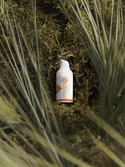 Frasco branco de creme para olhos calmante da Unnamed Cosmetics sobre musgo verde natural